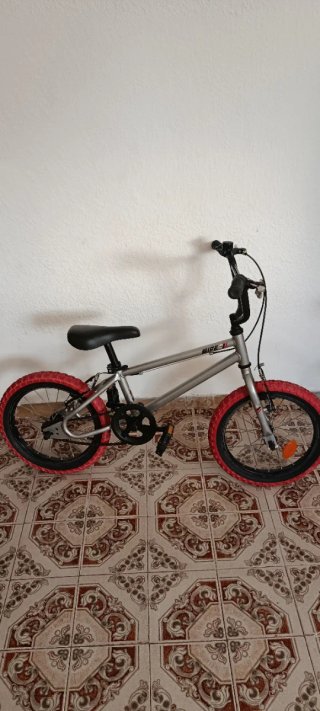 Bicicleta BMX plateada con ruedas rojas