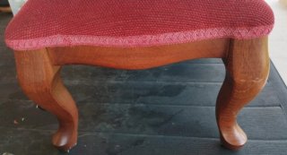 Taburete tapizado granate con patas de madera