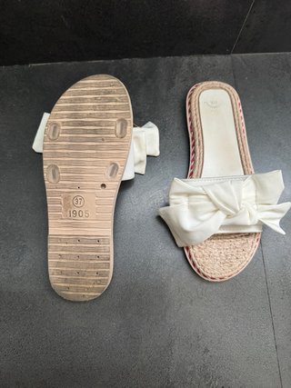 Chanclas planas blancas y beige.