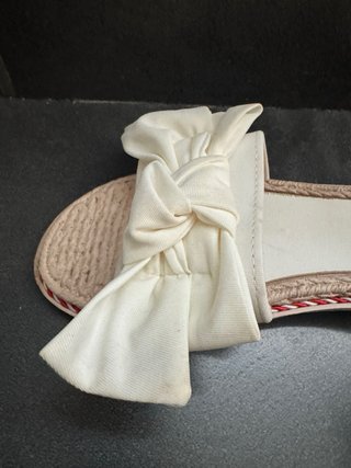Chanclas planas blancas y beige.