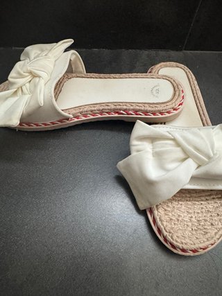 Chanclas planas blancas y beige.