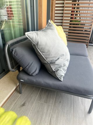 Sofá de exterior gris y cojín amarillo