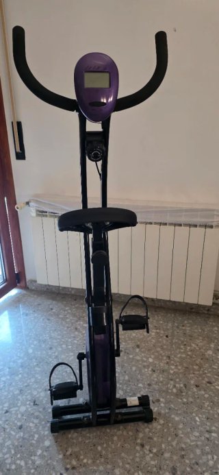 Bicicleta estática púrpura compacta