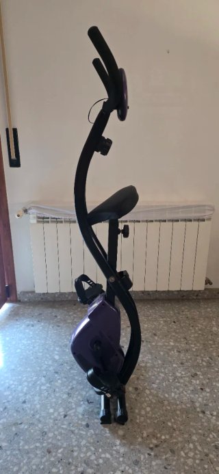 Bicicleta estática púrpura compacta
