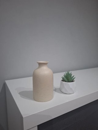 Jarrón beige y planta artificial verde