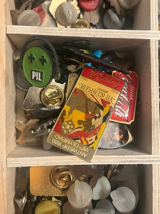 Caja de coleccionismo con pines y antigüedades