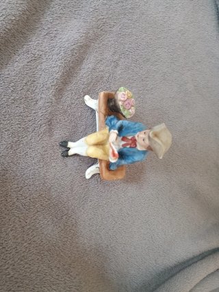 Muñeco de porcelana sentado en banco