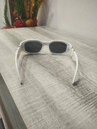 Gafas de sol blancas y negras con detalle dorado.