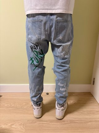 Pantalón streetwear desgarrado con texto.