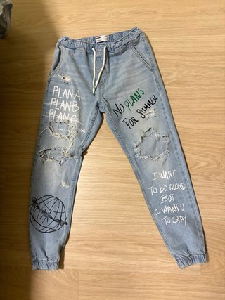 Pantalón streetwear desgarrado con texto.