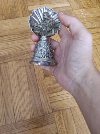 Campana metálica antigua con figura