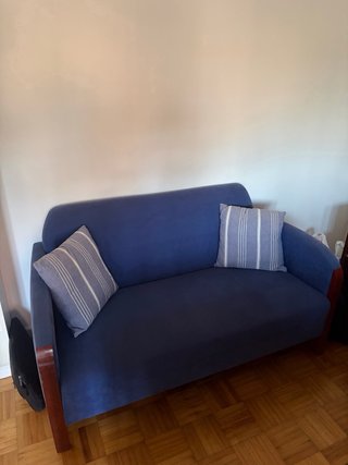 Sofá azul de tela y madera. Cómodo.