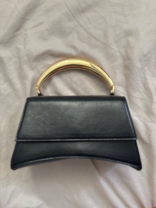 Bolso de mano negro con asa dorada