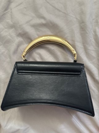 Bolso de mano negro con asa dorada