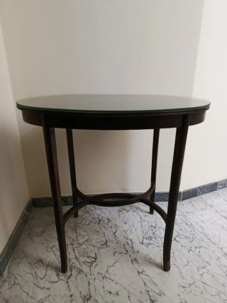 Mesa ovalada antigua de madera con cristal.