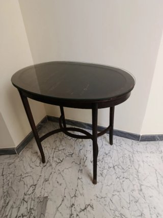Mesa ovalada antigua de madera con cristal.