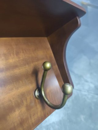 Perchero de madera con ganchos dorados.