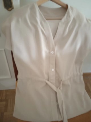 Blusa beige con cinturón.