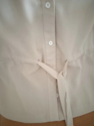 Blusa beige con cinturón.