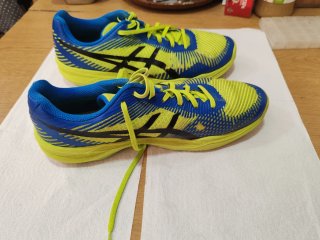 Zapatillas deportivas ASICS azules y amarillos.