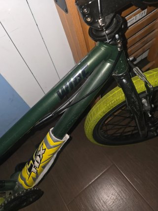 Bicicleta BMX verde con ruedas amarillas