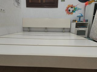 Cama somier de madera blanca con patas metálicas.