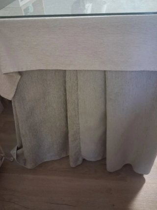 Mesa de camilla de madera con cristal y ropa.