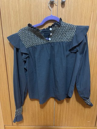 Blusa gris con volantes y bordado dorado.
