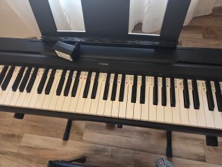 Teclado Yamaha con patas, pedal y banqueta.