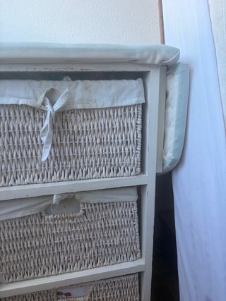 Mueble con cestas de mimbre y tabla de planchar