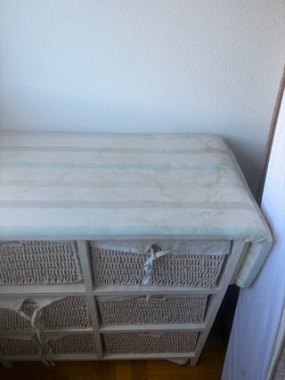 Mueble con cestas de mimbre y tabla de planchar