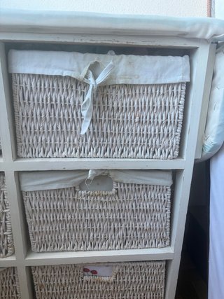 Mueble con cestas de mimbre y tabla de planchar