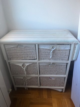 Mueble con cestas de mimbre y tabla de planchar