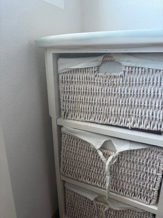Mueble con cestas de mimbre y tabla de planchar