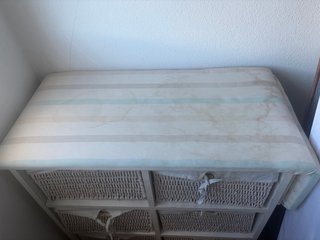 Mueble con cestas de mimbre y tabla de planchar