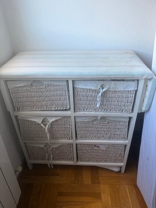 Mueble con cestas de mimbre y tabla de planchar