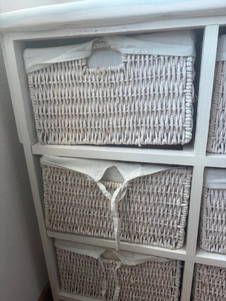 Mueble con cestas de mimbre y tabla de planchar