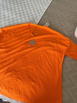 Camiseta naranja con estrella plateada.