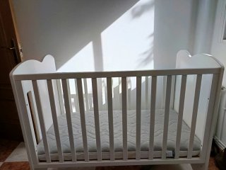 Cuna blanca con ruedas y diseño de casa