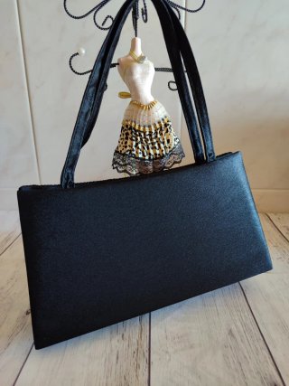Bolso de mano negro plisado con detalle joya