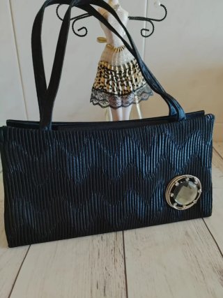 Bolso de mano negro plisado con detalle joya