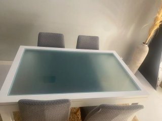 Mesa de comedor blanca con tapa de cristal.