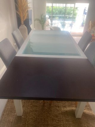 Mesa de comedor blanca con tapa de cristal.