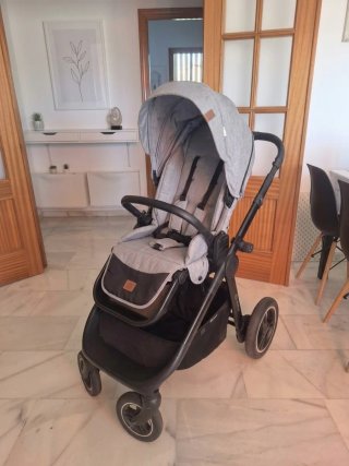 Carro de bebé Kinderkraft gris con capazo y bolso.