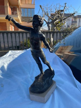 Statua in bronzo di ragazzo su roccia