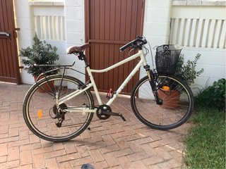 Bicicleta Decathlon urbana blanca con cesta.