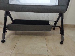 Cuna de bebé gris con mosquitera