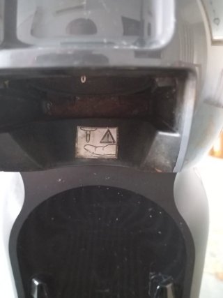 Cafetera Dolce Gusto Gris con un elemento oxidado.