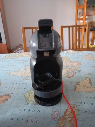 Cafetera Dolce Gusto Gris con un elemento oxidado.
