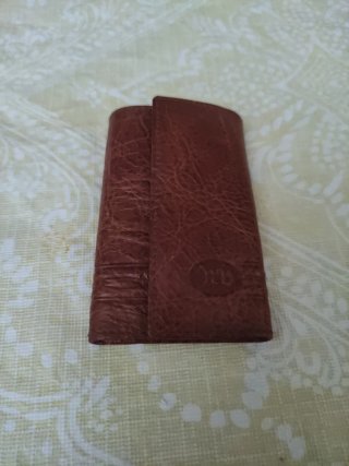 Cartera llavero de cuero marrón y dorado.